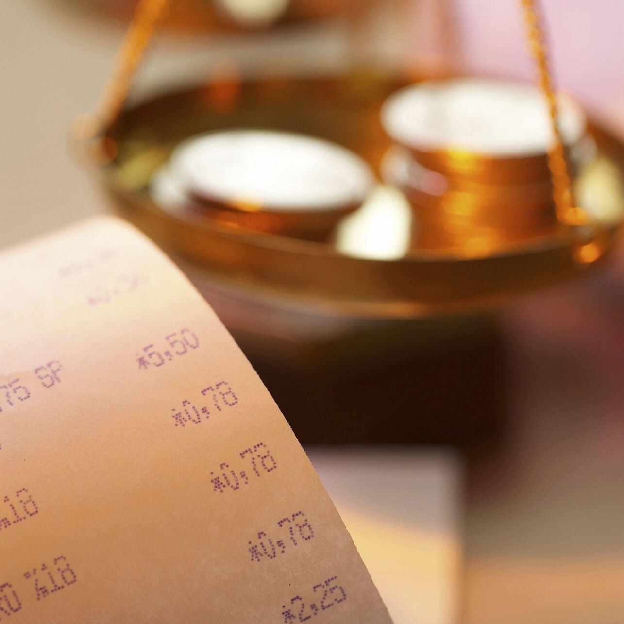 Kassenzettel mit Geldwaage im Hintergrund